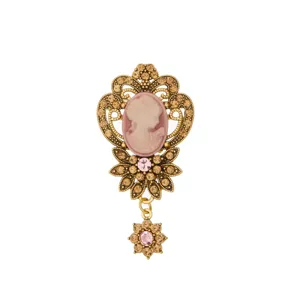 Exquisite vintage cameo brooch with pink rhinestones, ornate gold filigree detail accessory.