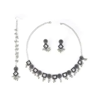 Close-up detail of bohemian ethnic style antique silver necklace earrings set with white stones.