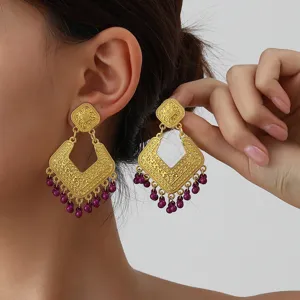 Vintage gold-tone statement earrings featuring intricate filigree rhombus designs and purple bead fringe.