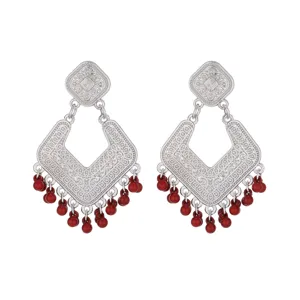 Detailed view of vintage silver-tone drop earrings with intricate filigree and red bead tassels.