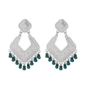 Detailed view of vintage silver filigree drop earrings with dark green beaded fringe.