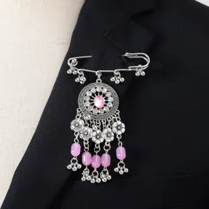 Primo piano di dettaglio di una spilla nappa vintage con fiori in metallo argento e perle.