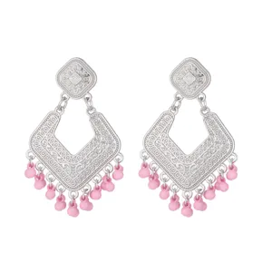 Close-up details of vintage silver geometric filigree earrings with cute pink beaded tassels.