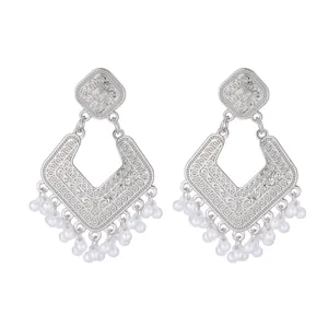 Close-up of vintage silver filigree drop earrings with delicate white pearl bead tassels.