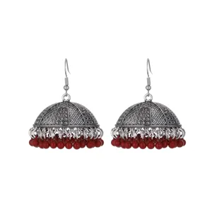 Detailed close-up of oxidized silver jhumka earrings with vibrant red beaded fringe tassels.