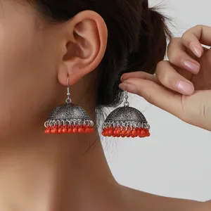 Detailed view of vintage ethnic jhumka earrings with red beaded tassels and silver tone.