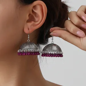 Detailed close-up shot of ethnic style silver jhumka earrings featuring purple beaded fringe.