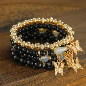 Detailed close-up view of the layered beaded bracelet with elegant gold butterfly charms.