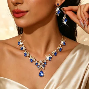 Detailopname van elegante goudkleurige bloemkristal ketting en oorbellen set met blauwe stenen.
