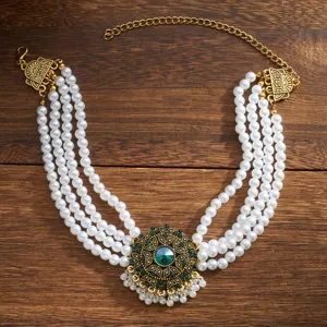 Detailaufnahme der mehrsträngigen Perlenkette mit goldenem Anhänger und grünem Kristall.