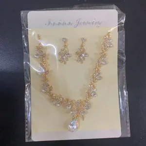 Gedetailleerde close-up van de gouden strass-bladeren ketting en oorbellen set op displaykaart.