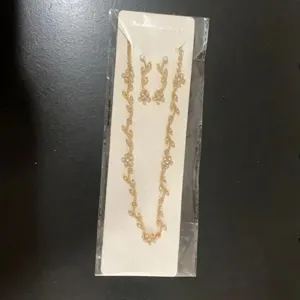 Detailed view of the gold-tone leaf pendant necklace and matching crystal rhinestone earrings set.