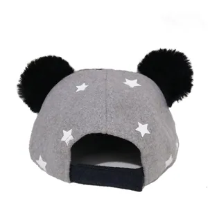 Close-up detail view of grey baby baseball cap with white stars and cute black pom-pom ears.