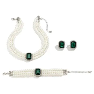 Detail view of multi-strand pearl jewelry set featuring emerald green crystal and earrings.