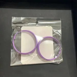 Close-up detail shot of minimalist purple hoop earrings on display card in transparent packaging.