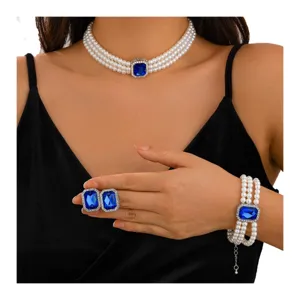 Detailed shot of retro pearl necklace bracelet and earrings set with blue crystal center.