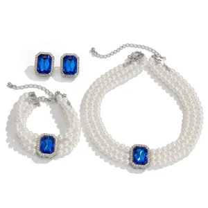 Elegant multi-layer pearl necklace bracelet earrings set with stunning blue gemstone.
