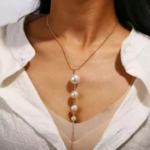 Vista cercana y detallada de un elegante collar dorado en Y con perlas colgantes.