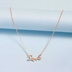 Delicado collar de clavícula con dije Love dorado adornado con brillantes piedras de circonio.