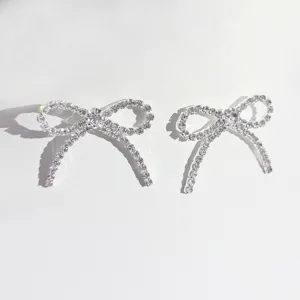 Silberne Strass Schleife Ohrringe Nahaufnahme Detail, glänzender funkelnder Modeschmuck.
