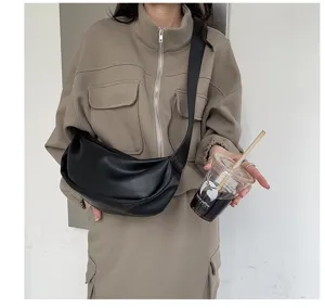 Detail view of black faux leather hobo crossbody bag with wide strap and soft pleats.