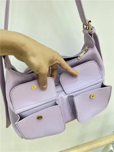 Detail view of purple leather shoulder bag showing multi pocket design and metal snap closure.