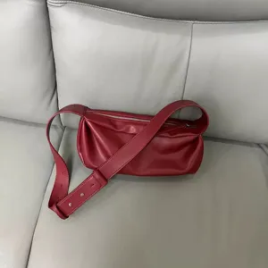 Red leather pleated shoulder bag detail view showcasing soft texture and wide strap.