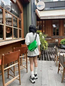 Detailed view of casual canvas crescent crossbody bag in bright green, ideal for summer travel.