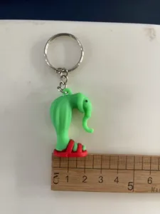 Gedetailleerd overzicht van creatieve abstracte groene olifanten sleutelhanger met rode schoenen.