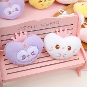 Close-up detail of cute heart plush keychains with crowns on a mini bench display.