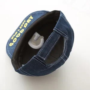 Infant denim baseball cap detail view, showing adjustable back strap and yellow letter brim.