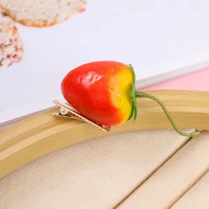 Close-up of cute 3D strawberry hairpin with realistic fruit design and secure metal clip.