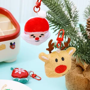 Detailed view of cute plush Christmas Santa and reindeer keychain charms on a holiday tree.