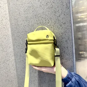 Compact yellow crossbody phone bag with top handle, zipper pocket and adjustable strap.