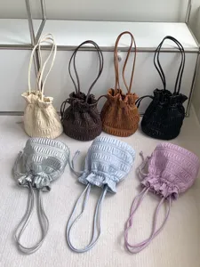 Detailed view of multiple colored gathered drawstring shoulder bags showcasing soft pleated design.