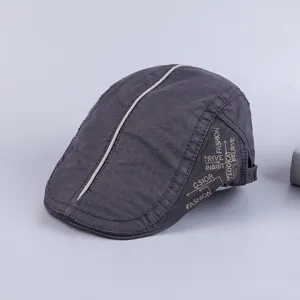 Close-up detail of the dark grey cotton flat cap featuring central white piping and stylish side embroidery.
