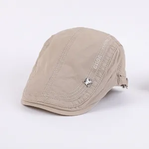 Khaki flat cap detail shot, stylish cotton newsboy hat featuring side embroidery and badge.