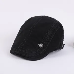 Black cotton flat cap for men, stylish retro ivy beret hat with metal badge and side text.