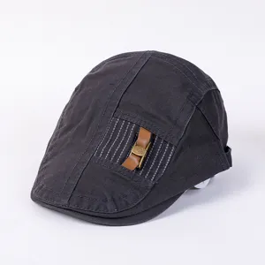 Detailed close-up of dark grey stylish flat cap with decorative leather strap and metal buckle.
