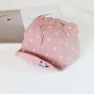 Pink polka dot baby baseball cap with cute bear ears and embroidered smiley brim for infants.