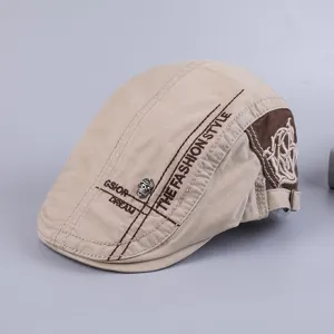 Close up of men cotton flat cap detail, khaki color with embroidery and skull rivet.