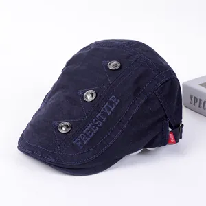 Detail view of the dark blue flat cap featuring freestyle embroidery and metal buttons.