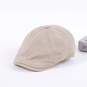 Detailed view of the beige cotton flat cap, featuring classic paneled construction and structured brim.