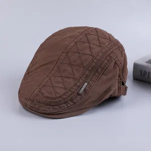 Detailed view of a brown cotton flat cap with quilted diamond pattern and stylish metal badge.