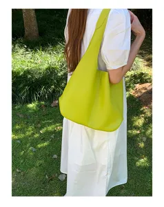 Outdoor detail shot of a lime green soft leather slouchy hobo shoulder bag worn on model.