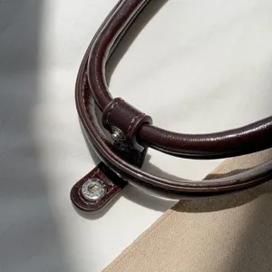 Close up detail shot of the premium dark brown oil wax leather handbag handle with metal snap.
