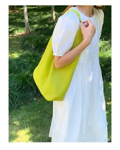 Detailed view of women's minimalist soft leather shoulder tote bag in outdoor scene.