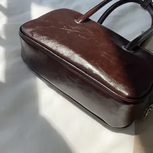 Close-up detail view of retro brown oil-wax leather shoulder bag surface and metal rings.