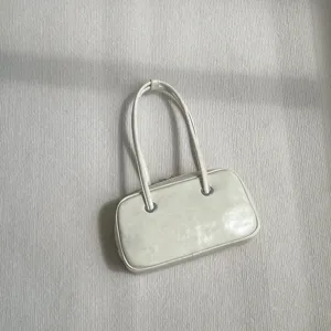 Detailed view of the minimalist shoulder bag showing smooth oil-wax texture and metal rings.