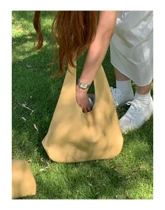Casual yellow soft leather slouchy shoulder bag detailed view in natural grass setting.